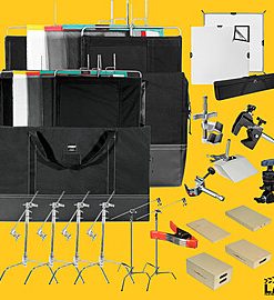 Full photography studio kit with bags, light stands, clamps, backdrops, and accessories on a yellow backdrop.